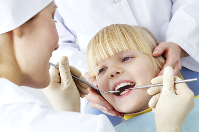Image of little girl having teeth checked by doctor and assistant